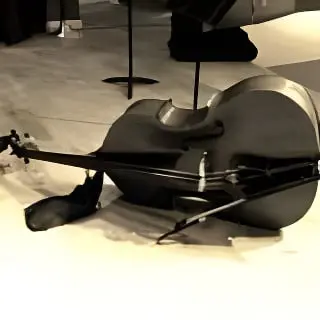 Upright bass lying on its side on a stage floor with its bow beside it